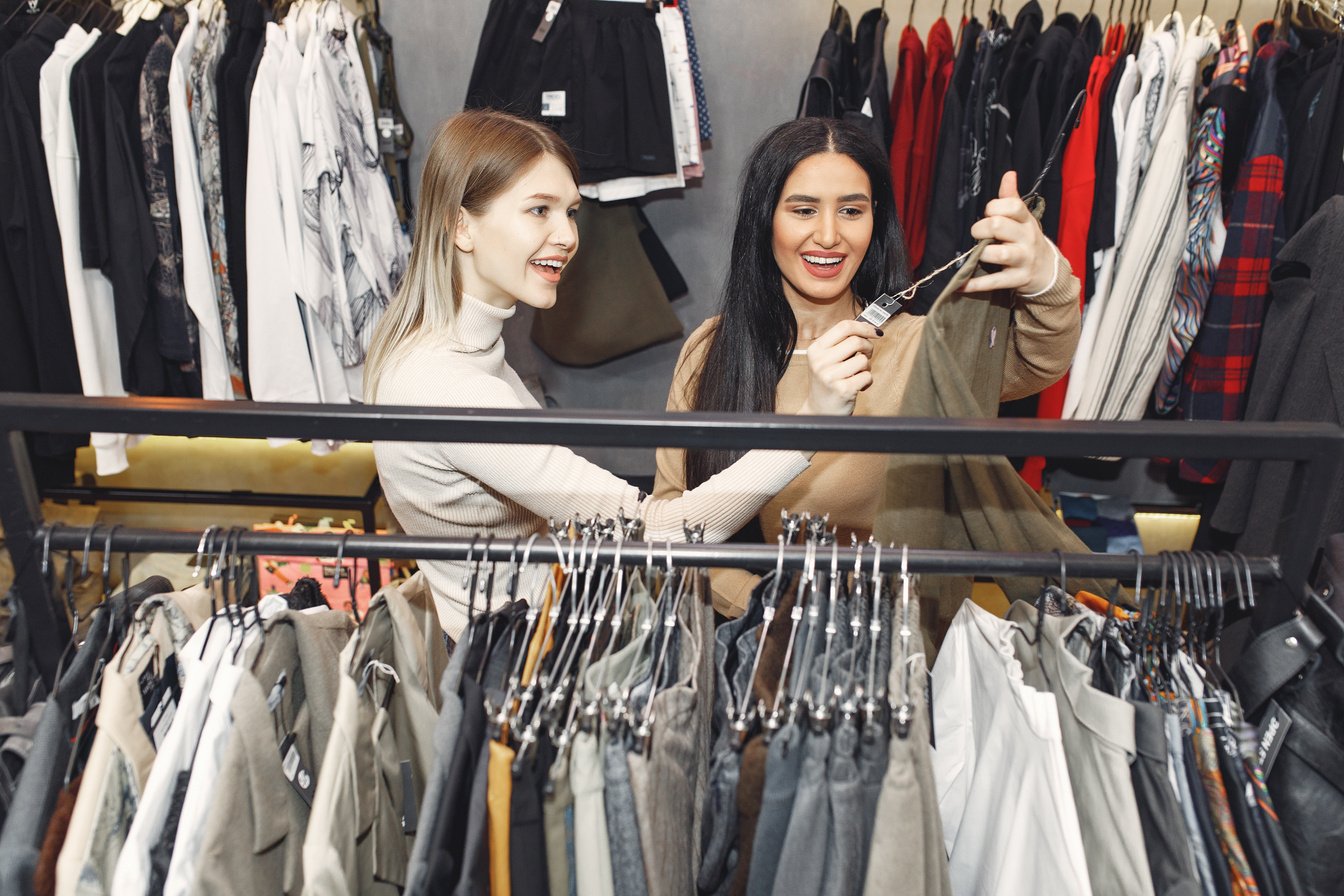 Happy friends choosing clothes in store